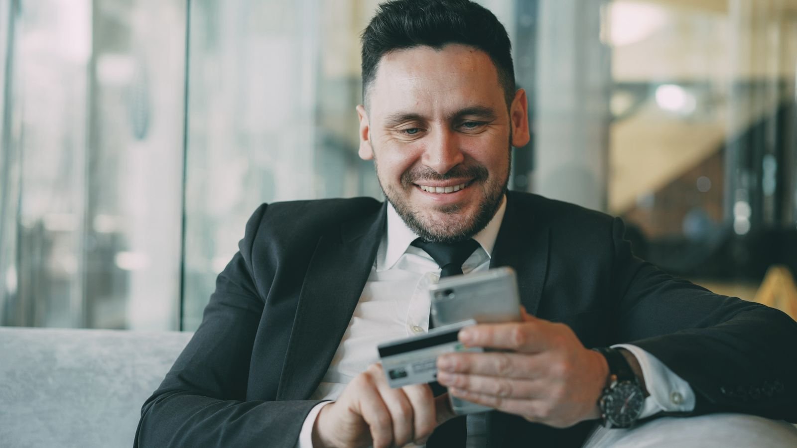 Businessman using online banking on a smartphone in a modern office